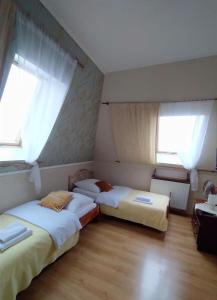 dwa łóżka w pokoju z dwoma oknami w obiekcie Pensjonat Hagi w mieście Horyniec