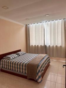 sypialnia z łóżkiem i oknem z zasłonami w obiekcie Casa em Tucuns w mieście Búzios