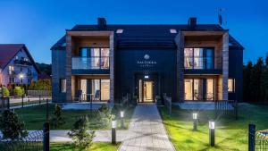 a house with a black facade with a pathway at Apartament w Nautikka Resort Krynica Morska in Krynica Morska