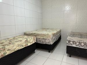 two twin beds in a room with white tiles at Casa Familiar - Guaibim in Guaibim
