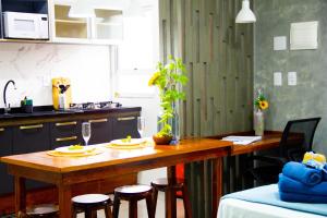 uma cozinha com uma mesa de madeira e algumas cadeiras em Studio Girassol em Florianópolis