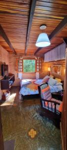 1 dormitorio con 2 camas y ventana grande en Ecos da Terra Chalés, en Monte Verde