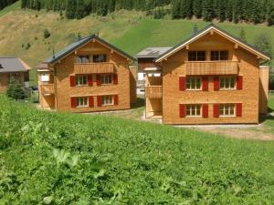 una casa con puertas rojas y un campo verde en Alpin Chalet Schröcken en Schröcken