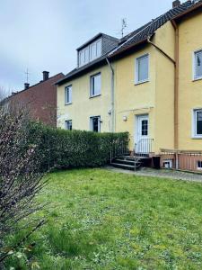 a yellow house with a yard in front of it at Easy to Düsseldorf Messe, 2-bedroom Apartment with kitchen and garden in Duisburg