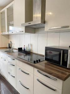 a kitchen with white cabinets and a black microwave at Easy to Düsseldorf Messe, 2-bedroom Apartment with kitchen and garden in Duisburg