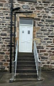 a white door on a stone building with stairs at Cullen Holiday Home in Cullen