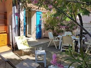 patio ze stołem i krzesłami oraz niebieskimi drzwiami w obiekcie Villa T3 Mezzanine Climatisée, Terrasse & Parking, 900m de la Plage - Saint-Cyprien Plage - FR-1-106-42 w mieście Saint-Cyprien