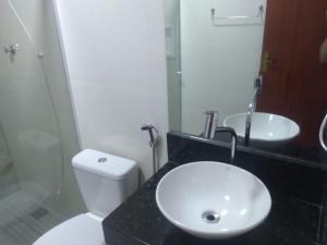 La salle de bains est pourvue de toilettes blanches et d'un lavabo. dans l'établissement Pousada Canoa dos Anjos suítes, à Arraial do Cabo