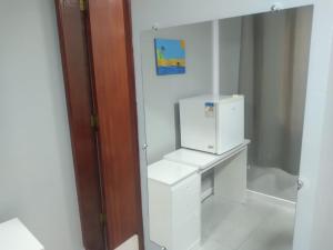 a small white kitchen with a small refrigerator at Pousada Canoa dos Anjos suítes in Arraial do Cabo