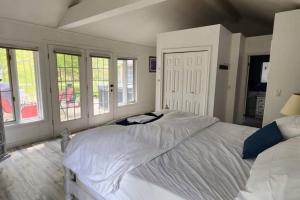 a bedroom with a large white bed and windows at Prince Edward County~Water View~FREE Pontoon Boat~Sandbanks Pass in West Lake