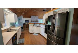 a kitchen with a stainless steel refrigerator and white cabinets at Prince Edward County~Water View~FREE Pontoon Boat~Sandbanks Pass in West Lake