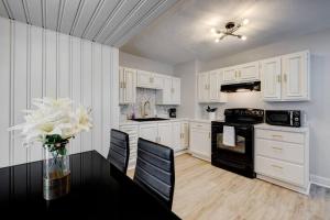 una cocina con armarios blancos y una mesa con un jarrón de flores en Cozy Henderson Home Close to Downtown Henderson, en Henderson
