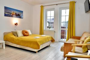 um quarto com uma cama com lençóis amarelos e janelas em Dom Wczasowy Chlapovia em Władysławowo