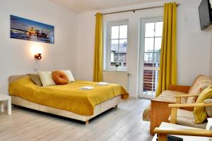 a bedroom with a bed with yellow sheets and windows at Bursztynek in Władysławowo