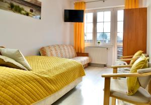 a bedroom with a yellow bed and a couch at Bursztynek in Władysławowo