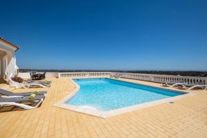 a swimming pool with chairs and the ocean in the background at Villa Casa Colina - Algarve - 7 Bedrooms, Private location in Estói