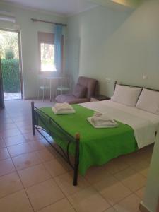 a bedroom with a bed with a green blanket on it at AGIOS NIKITAS DOLPHINS in Agios Nikitas