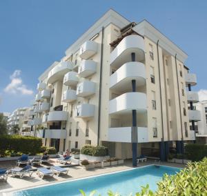 een groot appartementencomplex met een zwembad ervoor bij Green Holiday Flat with pool close to the beach in Bibione