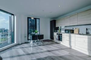 uma cozinha com armários brancos e uma mesa com cadeiras em Stunning 2-Bed Premium Apartment - Free WI-FI em Preston