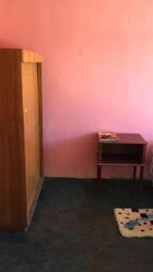 a room with a table and a pink wall at Habitación en Casa Familiar 