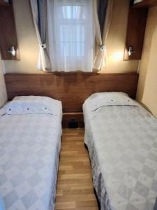 two beds in a small room with a window at Mobil home avec terrasse 4 personnes in Ambon