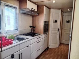 a small kitchen with a sink and a stove at Mobil home avec terrasse 4 personnes in Ambon