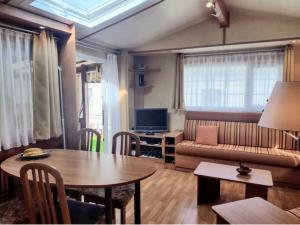 a living room with a table and a couch at Mobil home avec terrasse 4 personnes in Ambon