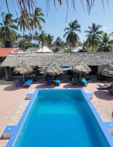 un complexe avec une piscine et des parasols dans l'établissement Amani Hotel Paje, à Paje