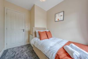 a bedroom with a bed with orange pillows on it at The Peytons Place in Chorley