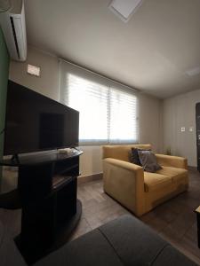 uma sala de estar com um sofá e uma televisão de ecrã plano em Departamento confortable em Mendoza