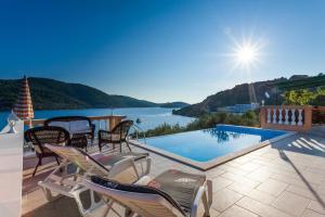 een patio met stoelen en een zwembad met uitzicht op het water bij Holiday Home Nina Plitvine in Vela Luka