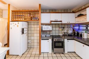 a kitchen with white appliances and white cabinets at Mansão Guará - com piscina, salão de jogos, churrasqueira e cozinha in Parnaíba