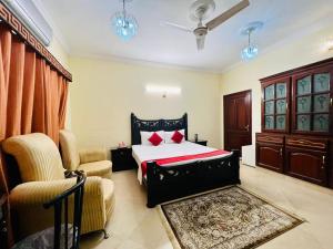 a bedroom with a bed and two chairs at Step Inn Guest House Islamabad in Islamabad