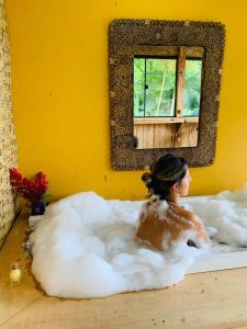 una donna in un bagno di schiuma in una stanza con uno specchio di Chales Sol Paraty a Parati