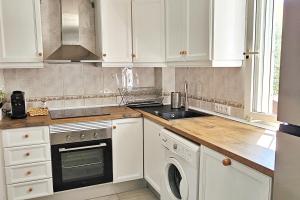 a kitchen with white cabinets and a sink and a dishwasher at House with 4 pools, Next to Beach in Gran Alacant