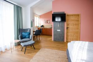 a living room with a bed and a kitchen with a refrigerator at Stadthotel Freilassing in Freilassing