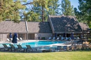 a pool with chairs and umbrellas next to a house at Mt Bachelor Village Resort Condo 19 Mi to Skiing! in Bend