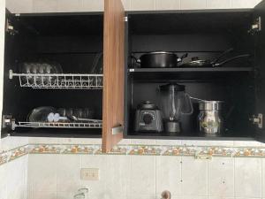 einen Küchenschrank mit Töpfen und Pfannen darin in der Unterkunft Cali Bella Alamos in Cali