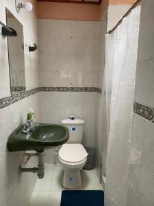 ein Badezimmer mit einem grünen Waschbecken und einem WC in der Unterkunft Cali Bella Alamos in Cali