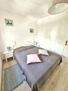 een slaapkamer met een groot bed met 2 roze kussens bij House with 4 pools, Next to Beach in Gran Alacant