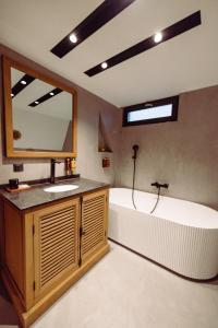 a bathroom with a tub and a sink and a mirror at A-BY THE LAKE - PRIVATE A FRAME VILLAS in Căciulaţi