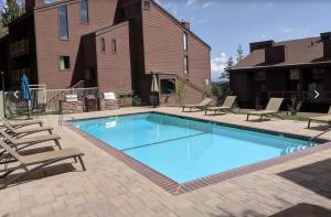 a large swimming pool with chairs and a building at #456 - Alpine High Retreat - Ski-In, Walk to Canyon Lodge in Mammoth Lakes
