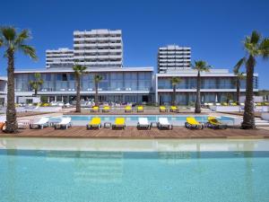 a resort with a pool and chairs and palm trees at Pestana Alvor South Beach Premium Suite Hotel in Alvor
