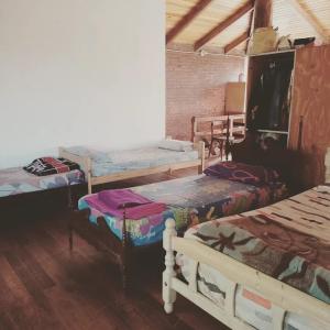 een kamer met 3 bedden in een kamer met houten vloeren bij CASA QUINCHO in Jesús María