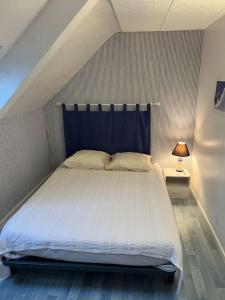 Schlafzimmer mit einem großen weißen Bett mit blauem Kopfteil in der Unterkunft Chez Nadia in Paimpol