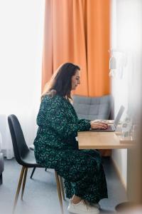 a woman sitting at a desk with a laptop at Stadthotel Freilassing in Freilassing