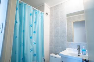 baño con cortina de ducha azul y lavamanos en Disfruta de un tranquilo departamento en el centro a pasos del Hipodromo en Santiago