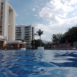 a swimming pool with blue water in front of buildings at Apartamento en entorno natural in Villeta