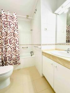 a bathroom with a toilet sink and a shower curtain at Adosado en Novo Atlantico Golf in Novo Sancti Petri