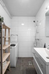 La salle de bains blanche est pourvue d'un lavabo et d'une douche. dans l'établissement Hidden gem near the Old Town Bridge, 40m² apt., à Trondheim